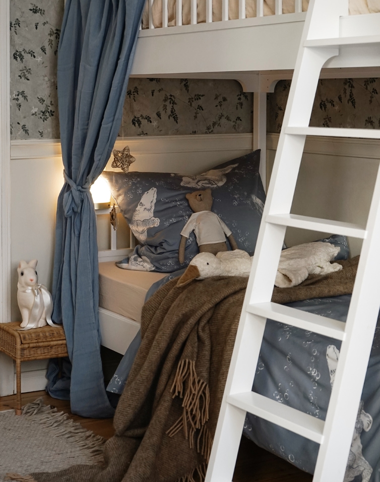 Gemütliches Hochbett mit blauer Tiermuster-Bettwäsche und brauner Decke im Kinderzimmer