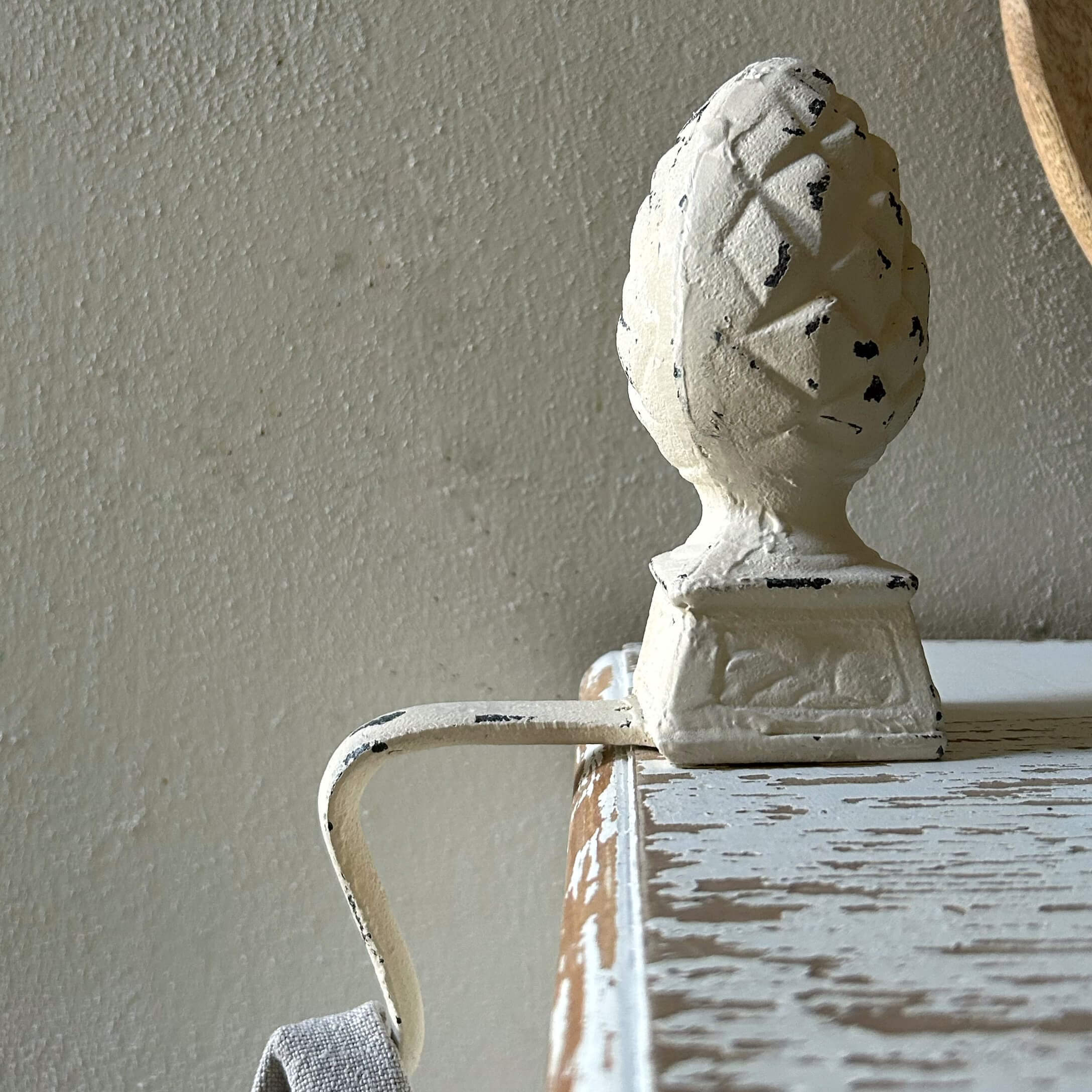 Weisser Metallgriff mit Zapfenornament auf antik wirkendem Holzmöbel